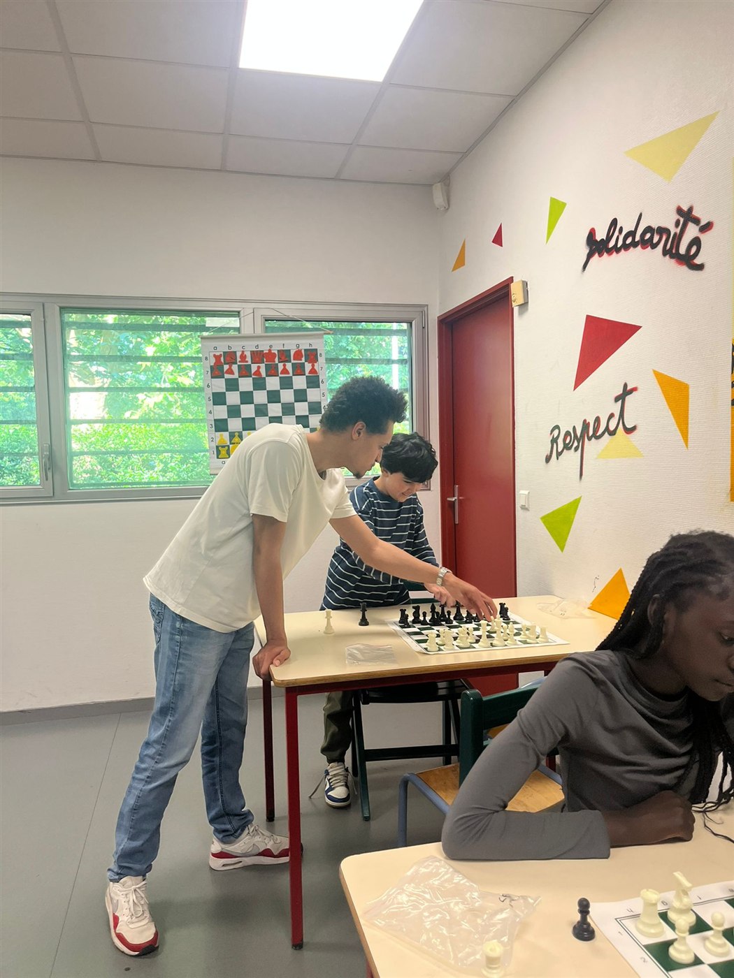 Samuel Alcindor explique une position devant un tableau d'échecs