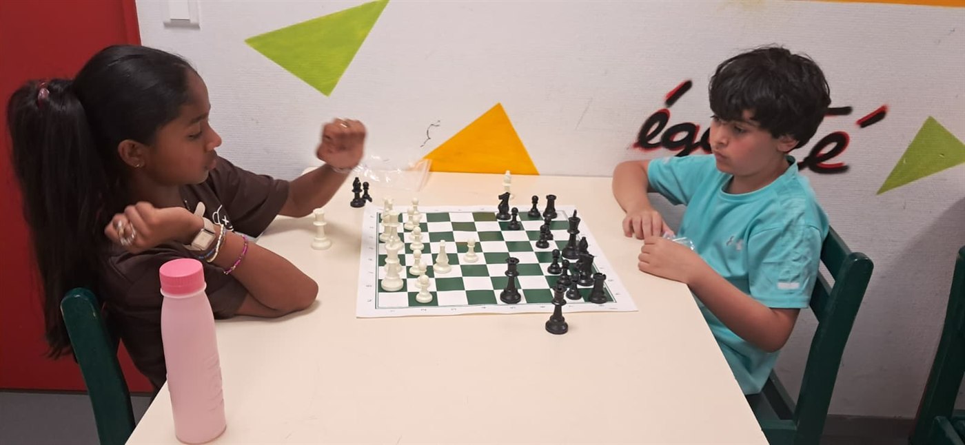 Deux élèves concentrés face à face autour d'un échiquier